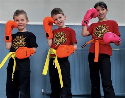 Three young Tiger Strike members wearing training gloves